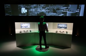 Man at fake control desk looking at display in an exhibition
