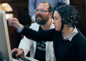 A woman wearing an EEG cap interacts with a screen