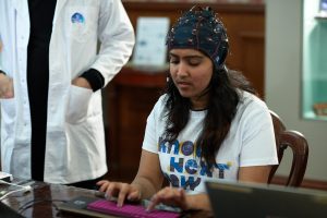 A woman wearing an EEG cap interacts with a modified keyboard