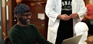 Researcher looks as man wearing EEG uses computer