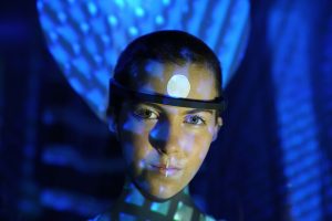 Person wearing a band around their head with a glowing ball at their forehead