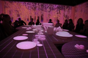 A tea party table lit with neon pink light