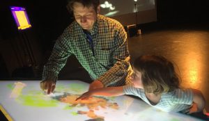 A man and young child interact with an augmented reality table