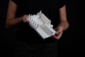 A person holding a 3D printed map of a garden with trees and architectural features