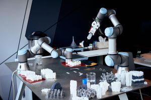 A table with 2 robot arms and a lot of different 3D printed prototypes