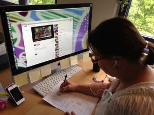 A woman sits in front of a screen taking notes